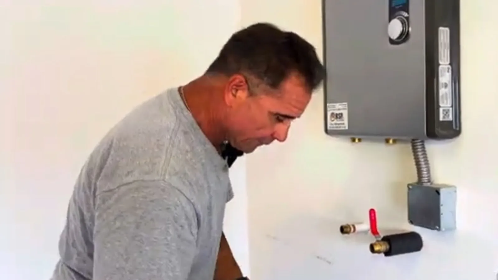 Technician servicing a wall-mounted tankless water heater